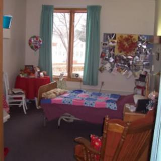 A cozy bedroom with colorful decor and a quilt-covered bed.