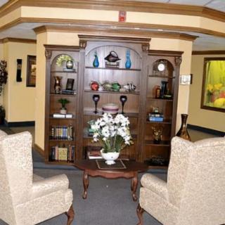 A cozy living room with a wooden bookshelf, decorative items, and comfortable armchairs.