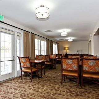 A spacious dining area with multiple tables and chairs, featuring modern lighting and large windows.