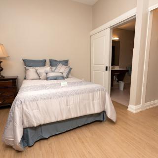 A neatly arranged bedroom with a bed, pillows, and a bedside lamp.