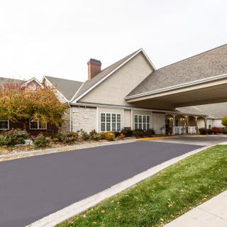 A suburban residential building with a covered driveway and landscaping.