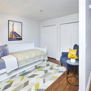 A cozy bedroom with a white daybed, colorful rug, and modern decor.