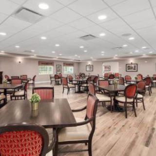 An elegant dining area featuring arranged tables and chairs, with bright lighting and wood flooring.