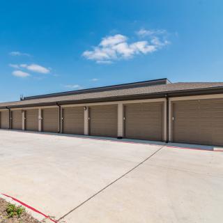 Row of garages with closed doors under a clear blue sky.