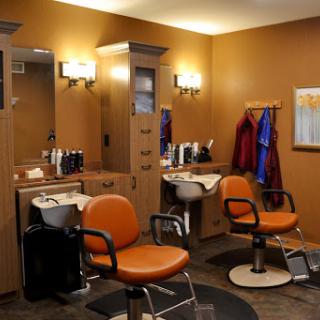 A modern barber shop interior featuring orange chairs and well-organized workstations.