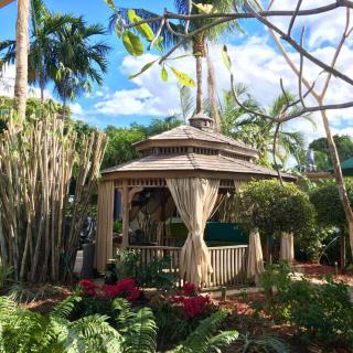 A serene tropical garden with a charming gazebo surrounded by lush greenery and colorful flowers.