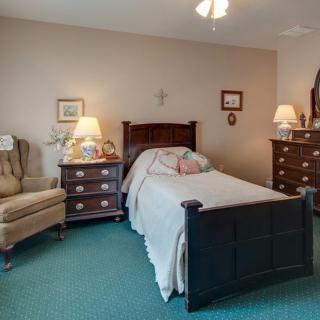 A cozy bedroom with a single bed, dresser, and bedside tables with lamps.