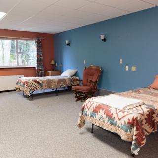 A cozy bedroom with two beds, featuring colorful walls and a large window.