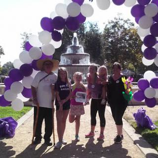 A group of five people enjoying a sunny day at a park event under a decorative balloon arch.