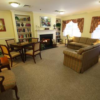 A cozy living room interior with a sofa, chairs, table, and a fireplace.