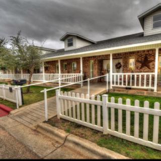 A charming house with a welcoming porch and white picket fence under a cloudy sky.