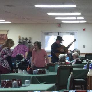 A lively music performance taking place in a dining area with seniors enjoying the entertainment.