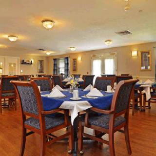 A spacious dining room with neatly arranged tables and chairs, featuring blue tablecloths and elegant decor.