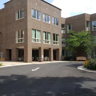 A modern brick building with large windows and a landscaped entrance.