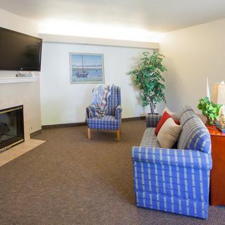 A cozy living room with a sofa, armchair, television, and fireplace.