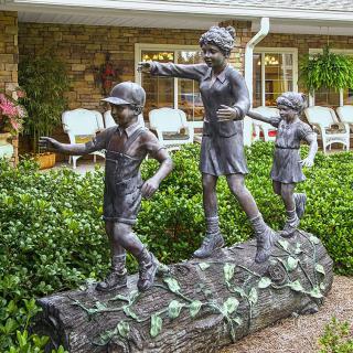 Sculpture of children playing in a garden setting.