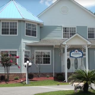 A two-story residential house with a light blue exterior and a well-maintained front yard.