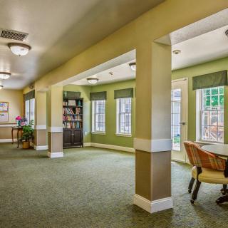 A spacious and well-lit room with green carpet, featuring a sitting area and large windows.