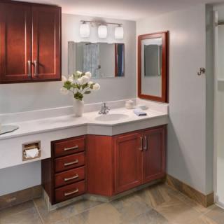 A modern bathroom vanity with a wooden cabinet, decorative flowers, and bright lighting.