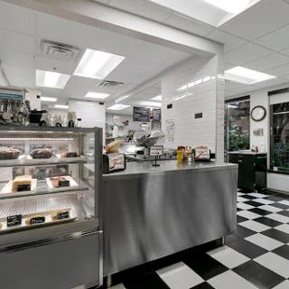 A modern restaurant kitchen featuring a stainless steel counter and a display case for food items.