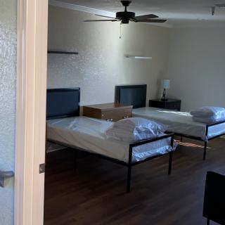 A minimalist bedroom with two beds and a ceiling fan.