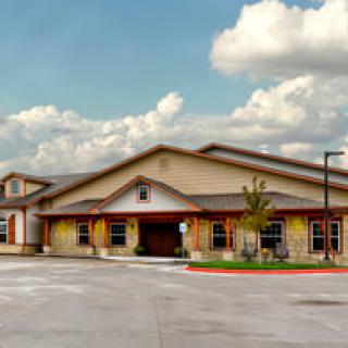 A large, single-story building with a driveway, set against a cloudy sky.