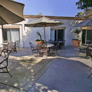 A sunny outdoor patio with tables, chairs, and large umbrellas.