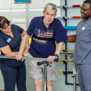 A healthcare team assists a patient during physical therapy.