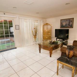 A cozy living room with elegant furniture, featuring a television and glass doors leading to the outside.