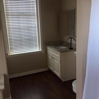 A small bathroom with a window, sink, and toilet.