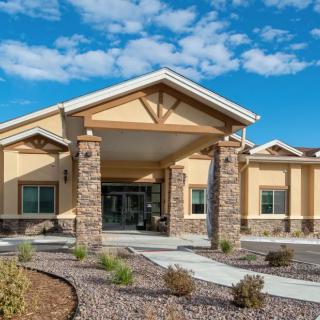 A modern building entrance with stone pillars and a landscaped front.