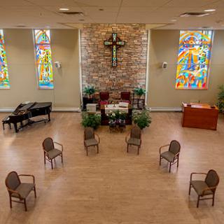 A serene church interior featuring stained glass windows and arranged seating for gatherings.