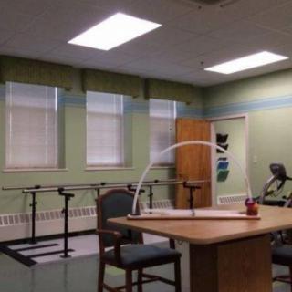 A therapy room equipped with exercise bars, a table, and chairs for rehabilitation purposes.