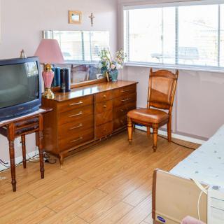 A cozy bedroom with vintage furniture, including a TV, dresser, and chair.