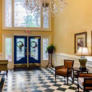 Elegant lobby with a checkered floor, chandelier, and inviting seating.