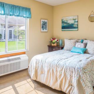 A cozy bedroom with a large window, colorful bedding, and tasteful decor.
