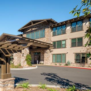 A modern residential building with a landscaped entrance under a clear blue sky.