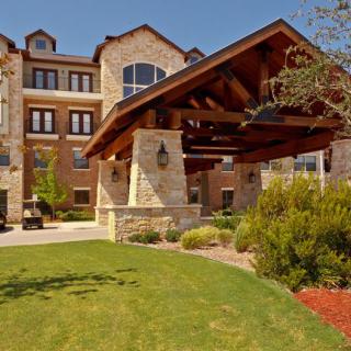 A beautiful residential building with stone and wooden architecture surrounded by lush greenery.