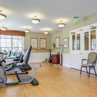 A well-lit exercise room featuring stationary bikes and wooden flooring.