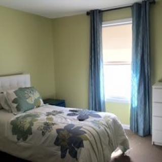 A cozy bedroom with a single bed and blue curtains.