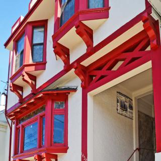 A residential building featuring distinctive red accents on bay windows and structural elements.