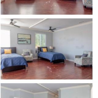 A spacious bedroom featuring two beds, armchairs, and ceiling fans on a hardwood floor.