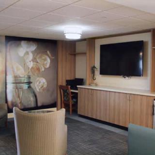 A modern lounge area featuring a large television, comfortable seating, and artistic wall decor.