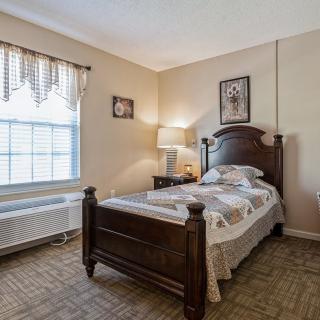 A cozy bedroom with a single bed and a lamp by the side.