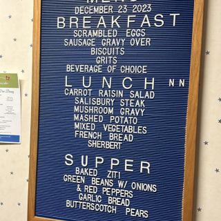 Menu board displaying meal options for December 23, 2023, including breakfast, lunch, and supper items.