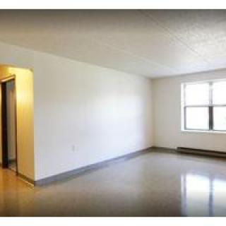 An empty room with a window and plain walls.