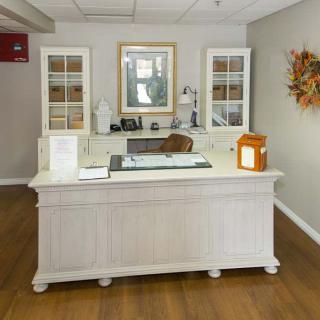 A neatly organized reception desk in an office setting with white furniture and decorative elements.