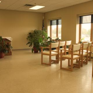 A serene waiting area with wooden chairs and a potted plant, bathed in natural light from the windows.