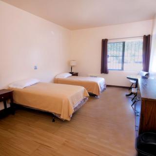 A simple bedroom with two twin beds and basic furnishings.