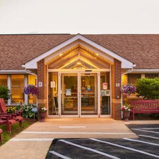 A welcoming entrance to a brick building, adorned with flowers and benches.